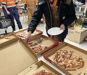 Expeditioners in the carpenters building for Friday drinks eating pizza