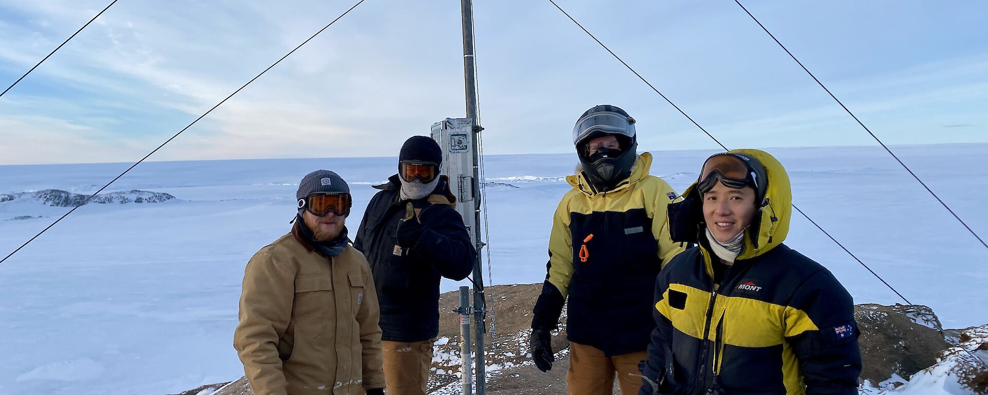 Casey winter expeditioners in a group photo in front an antenna in the snow