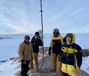 Casey winter expeditioners in a group photo in front an antenna in the snow