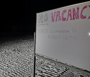 A sign in the snow reading  'No vacancy - nearest accommodation is Robbo's hut!!'