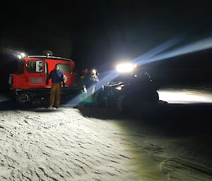 A Hagglund and Polaris General in the snow at night with beams on
