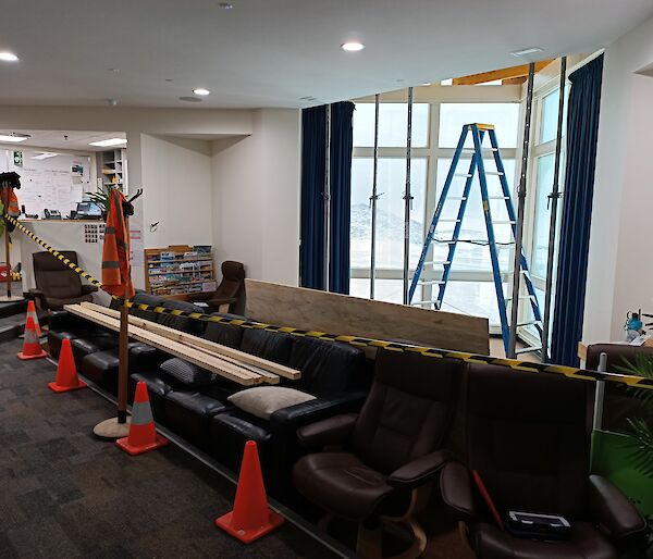 A large window, cordoned off with hazard tape and cones. Step ladders are placed in front of the window.