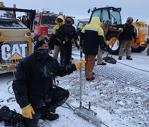 A man next to a Tirfor winch ready for action.  Tractors in a line behind him.