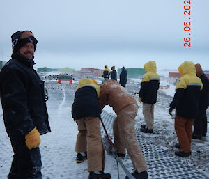 2 people operate the Tirfor winch while others watch the proceedings.