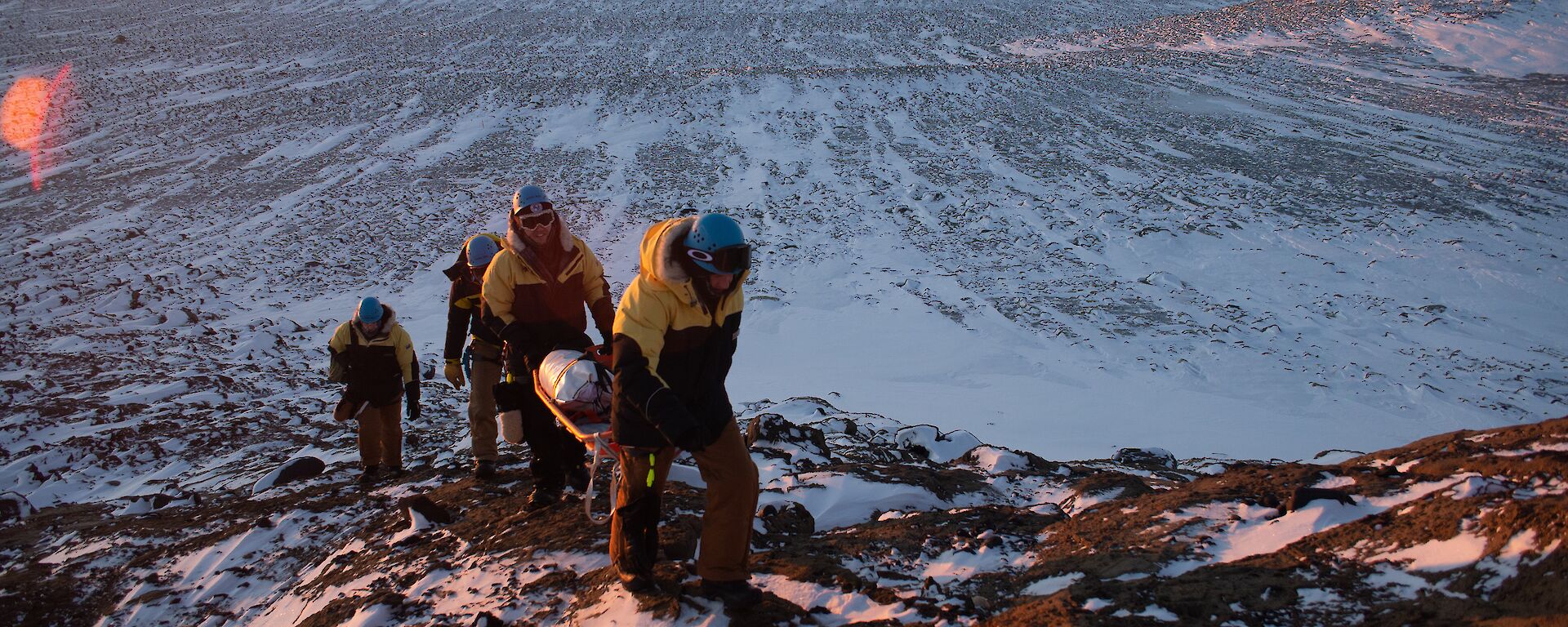 A group of people walking a stretcher up a hill