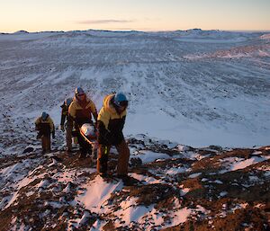 A group of people walking a stretcher up a hill