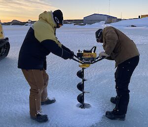 Two expeditioners using a petrol sea ice drill to bore through sea ice in Horseshoe Harbour