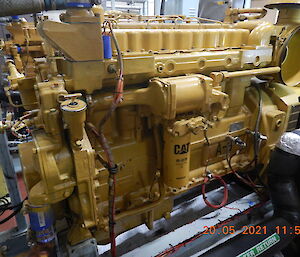 A large yellow generator engine in a workshop