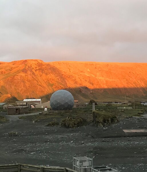 A view of the buildings on station.  The mountain behind has been lit orange by the sunset.