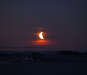 A dark sky and foreground with a bright cresent moon