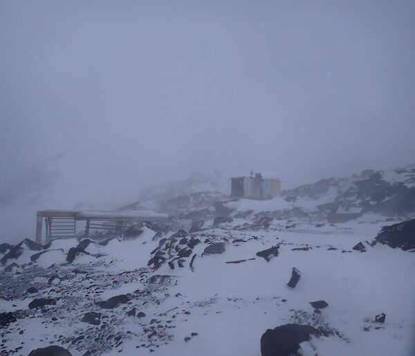 A blizzard scene with a small hut visible through the blowy snow