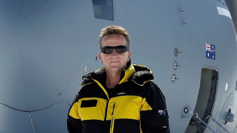 A man in yellow and black protective clothing standing in front of a RAAF aeroplane