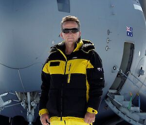 Man in yellow and black jacket standing in front of RAAF aeroplane