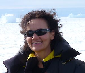 Woman in puffy jacket in front of icebergs.