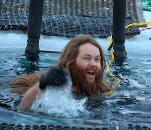 A man with long hair and a beard swimming in cold water