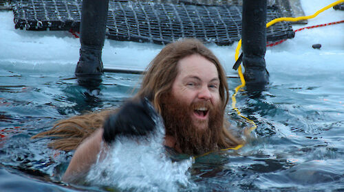 A man with long hair and a beard swimming in cold water