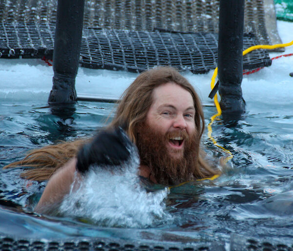 A man with long hair and a beard swimming in cold water
