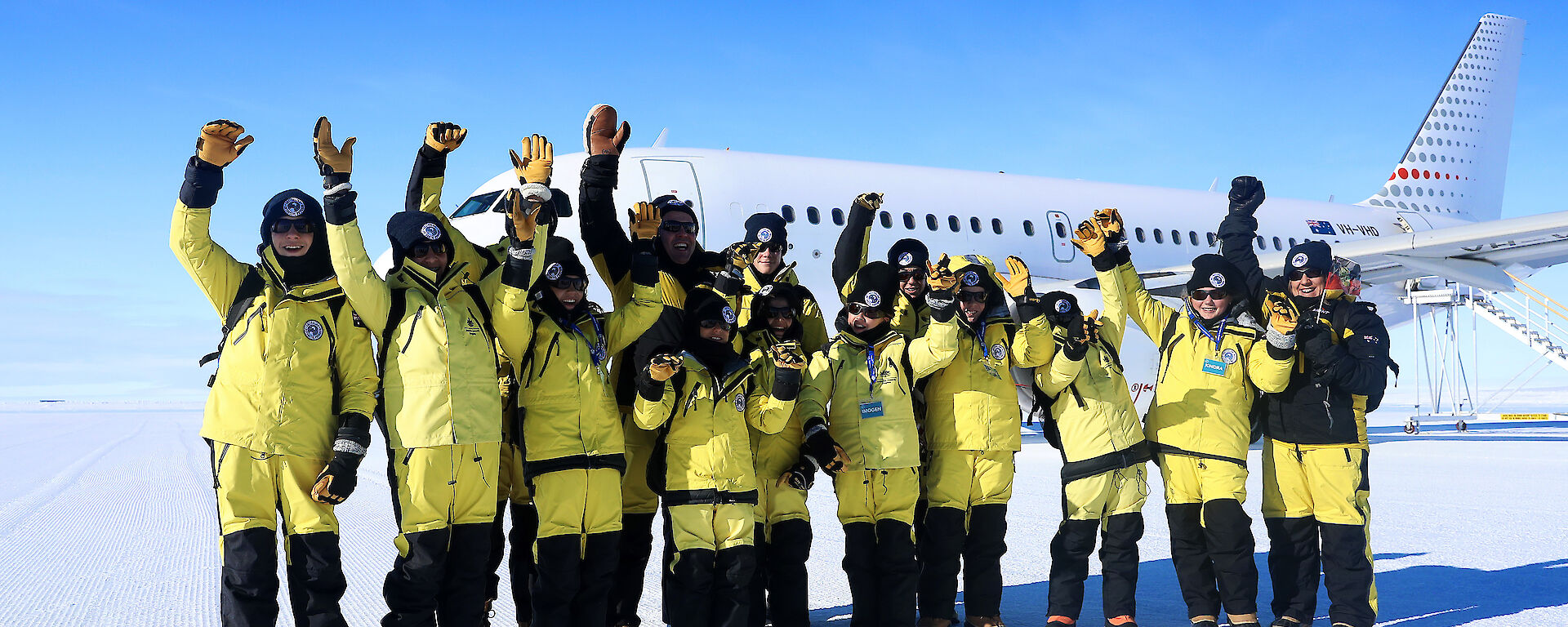 School children dressed in Antarctic clothing in front of an A319 aircraft in Antarctica.