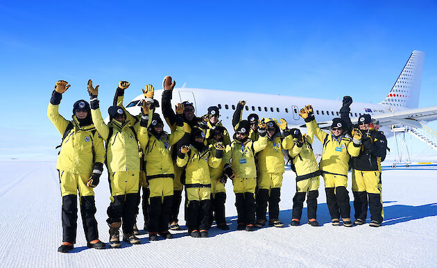 School children dressed in Antarctic clothing in front of an A319 aircraft in Antarctica.