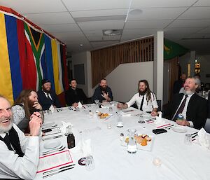 A table of diners laughing and some smiling to camera.