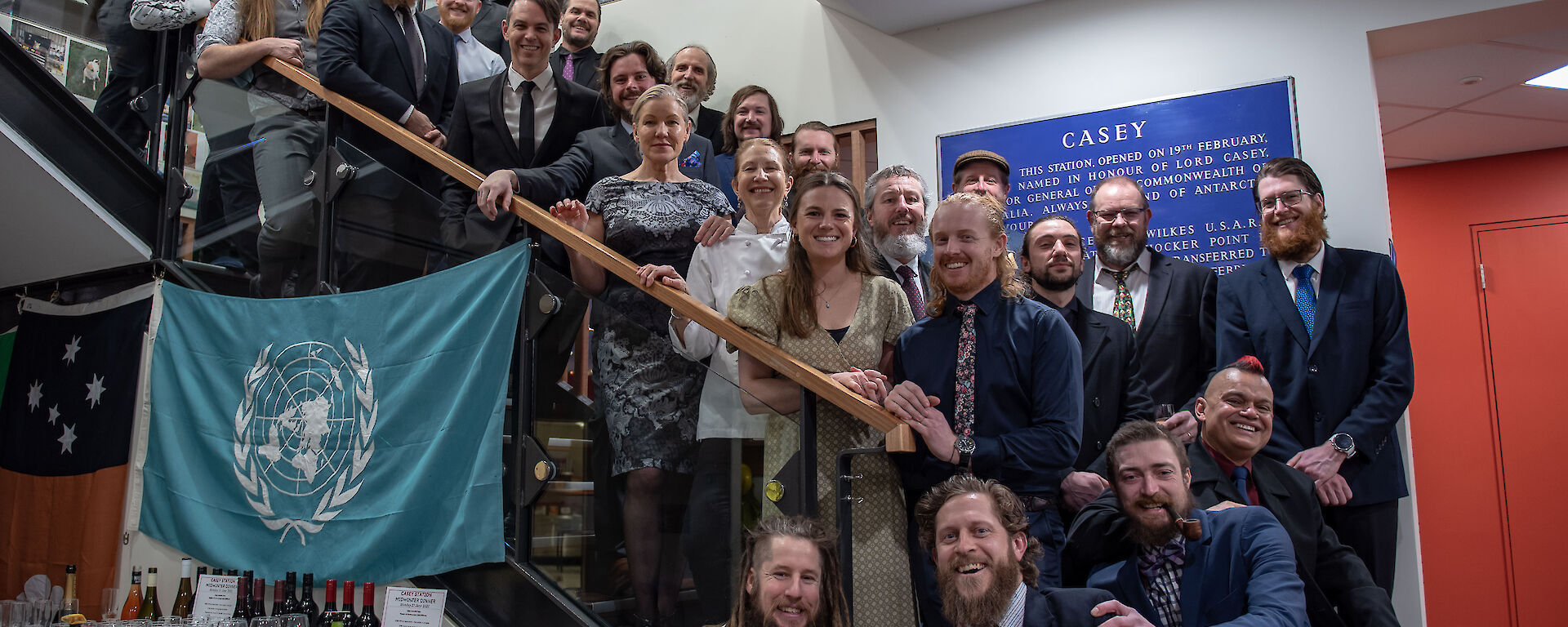 A large group of people standing on some stairs and smiling to camera