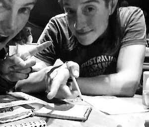 Two people playing a dice game, one pointing to a row of 5 dice all showing the number 4