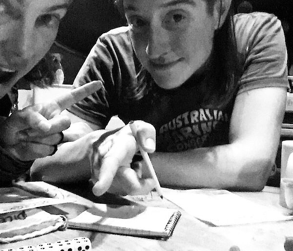Two people playing a dice game, one pointing to a row of 5 dice all showing the number 4