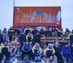 A group of people posing for a picture around the Davis Station sign