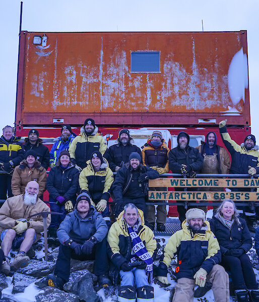 A group of people posing for a picture around the Davis Station sign