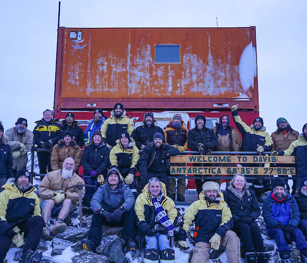 A group of people posing for a picture around the Davis Station sign