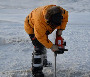 Expeditioner cutting lines in the sea ice with a chainsaw.