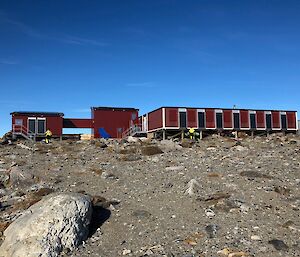 Boxy brown building on ice-free rocky ground.