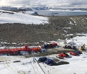 Red buildings from the air in snowy landscape with a bay visible in the distance.