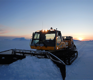 Large machine moving snow in twilight.