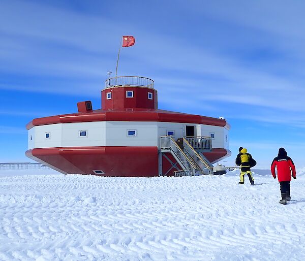 Red and white futuristic building in snowy landscape.