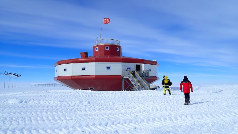 Red and white futuristic building in snowy landscape.