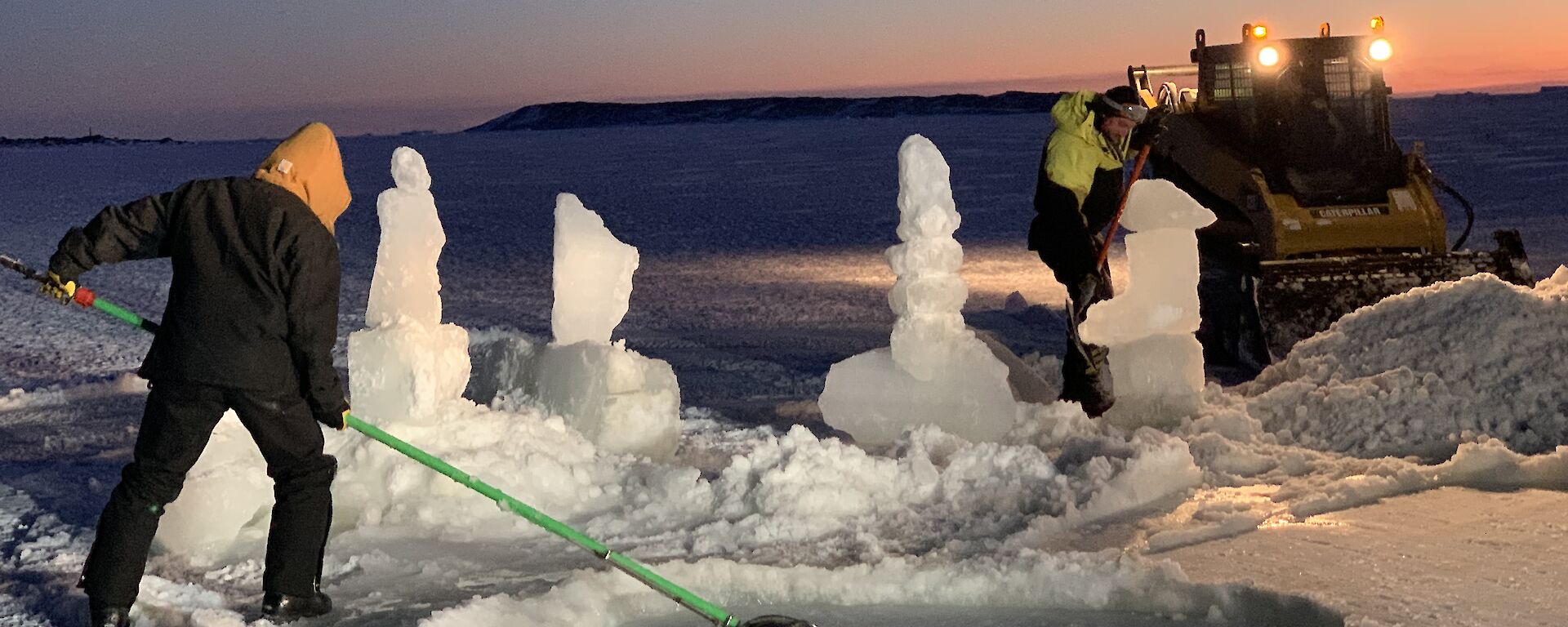 A man is scooping reformed ice out of an ice hole pool with ice sculptures around it.