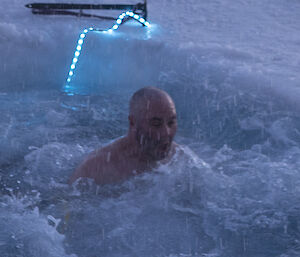 A man swimming in an ice hole looks shocked by the icy cold water