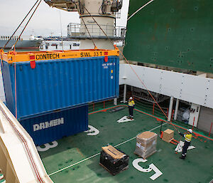 A shipping container being craned into place on the ship's foredeck