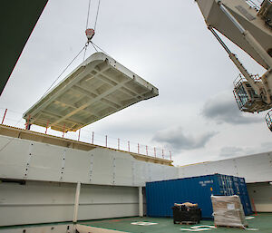 A crane lifting a large flat piece of steel.