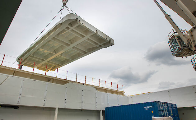 A crane lifting a large flat piece of steel.