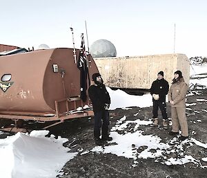 Three expeditioners standing in front of the Australian flag mounted on a RIMIT van to reenact the 1954 Mawson flag raising ceremony.