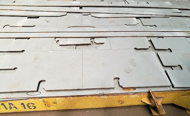 Flat steel plate with different shapes cut out.