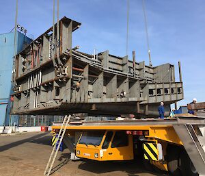 Steel panels constructed into a block being lifted off a tray.