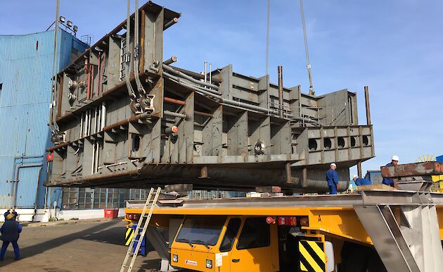 Steel panels constructed into a block being lifted off a tray.