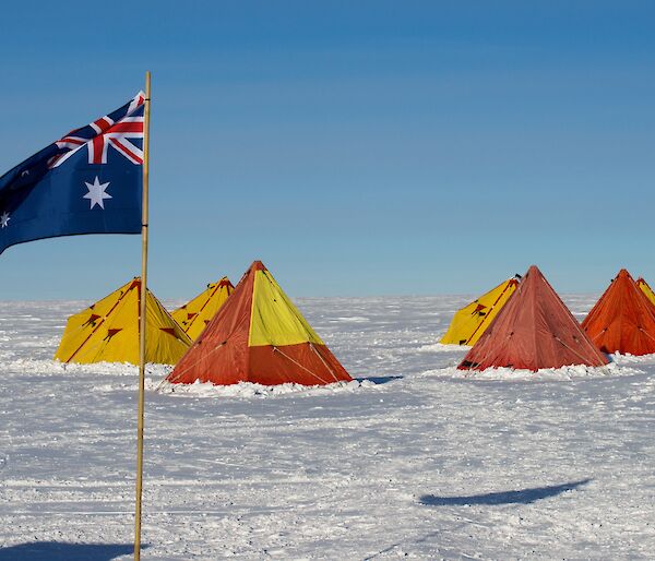 Red and yellow tents in the snow with an Australian flag flying