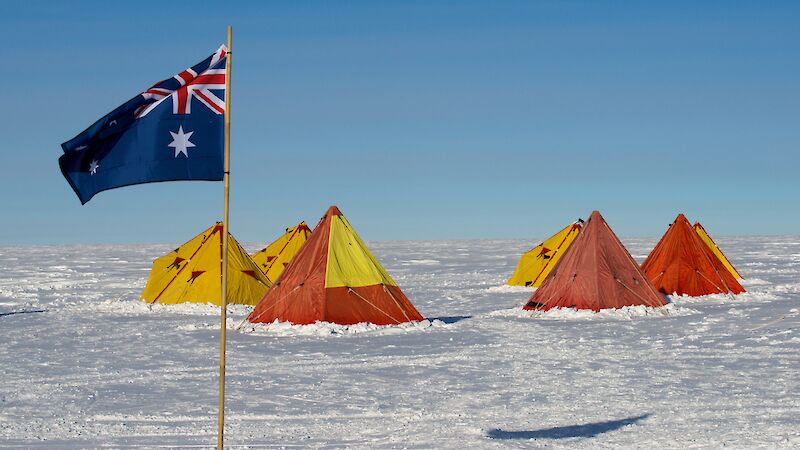 Red and yellow tents in the snow with an Australian flag flying