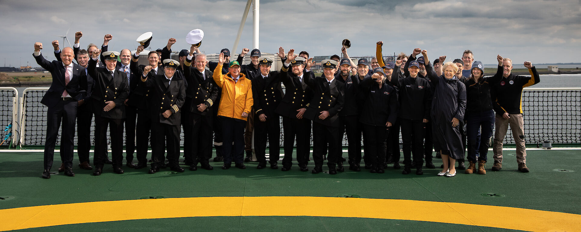 People giving three cheers under an Australian flag on the helideck of Nuyina.