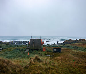 A small hut facing the ocean under grey skies