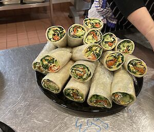 A plate of salad wraps on a kitchen bench